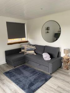 a living room with a gray couch and a mirror at Devon River Glamping Pods in Alloa
