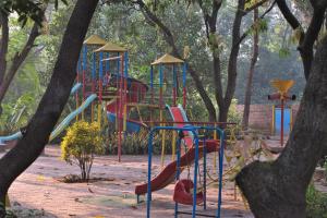 a playground with a slide in a park with trees at Srushti Farms Resort in Vasind