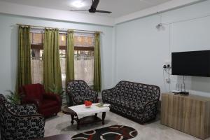 a living room with chairs and a flat screen tv at Jahnabee's Homestay in Guwahati