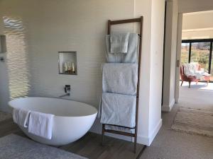 a bathroom with a white bath tub and towels at Walkersons Estate- Outcrop in Dullstroom