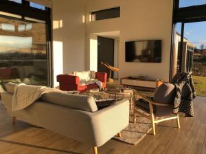 a living room with a couch and chairs and a tv at Walkersons Estate- Outcrop in Dullstroom