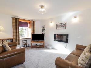 a living room with a couch and a flat screen tv at 19 Reidhaven Street in Banff