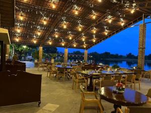 a restaurant with tables and chairs and a view of the water at Shikarbadi Hotel - Heritage by HRH Group of Hotels in Udaipur