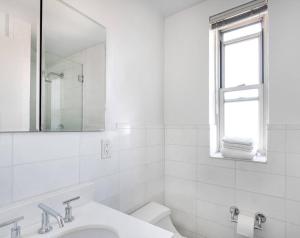 a white bathroom with a sink and a mirror at Lovely 4 Bedroom Apt in Midtown West in New York