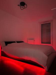 1 dormitorio con 1 cama con luz roja en Appartement neuf, tout équipé ! en Eaubonne