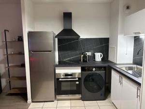 cocina con nevera de acero inoxidable y lavavajillas en Appartement neuf, tout équipé ! en Eaubonne