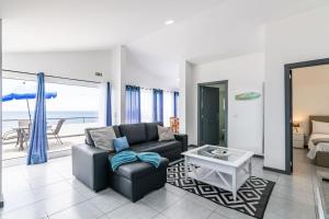 un soggiorno con un divano e un tavolo di Esterinha's Sunset Apartment by GALMI a Estreito da Calheta Altre 24 foto