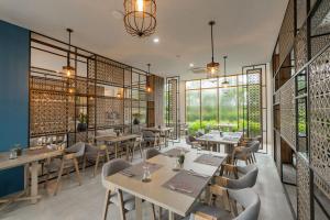 un restaurant avec des tables, des chaises et des fenêtres dans l'établissement Bella Nara Phuket Naiyang Beach, à Nai Yang Beach