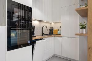 a kitchen with white cabinets and a black oven at Lux Kraków Apartment with Parking & AC just 1,5 km from Main Square by Renters Prestige in Krakow