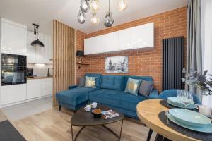 a living room with a blue couch and a brick wall at Lux Kraków Apartment with Parking & AC just 1,5 km from Main Square by Renters Prestige in Krakow
