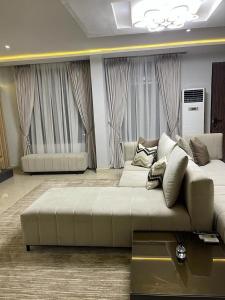 een woonkamer met een grote witte bank en ramen bij Dominion Court in Lagos