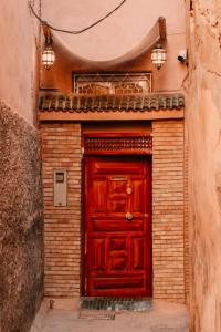 une porte rouge dans un bâtiment en briques avec deux lumières dans l'établissement Riad Fz Marrakech, à Marrakech