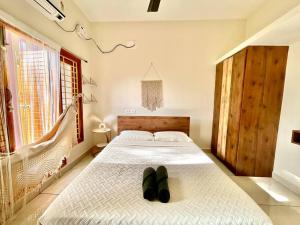 een slaapkamer met een bed met een paar schoenen erop bij Villa Porto' Lux beach house', Pondicherry in Pondicherry