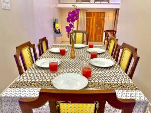 een tafel met borden en een vaas met bloemen erop bij Villa Porto' Lux beach house', Pondicherry in Pondicherry