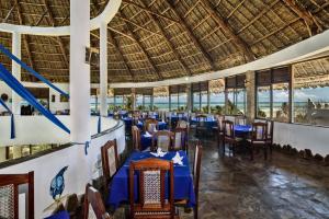 a restaurant with blue tables and chairs and a large ceiling at Jacaranda Beach Resort in Watamu
