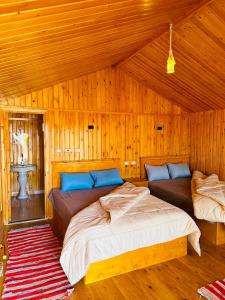 two beds in a room with wooden walls at Magic land taba camp in Taba