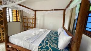 sypialnia z łóżkiem z baldachimem w pokoju w obiekcie Aquarium Beach House w mieście Nungwi