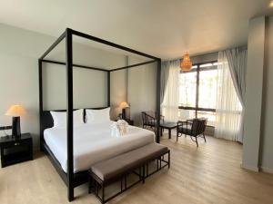 um quarto com uma cama de dossel, uma mesa e cadeiras em O2 The Residence โอทู เดอะ เรสซิเดนซ์ em Kanchanaburi