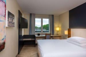 um quarto de hotel com uma cama, uma secretária e uma janela em Essential by Dorint Köln-Junkersdorf em Colônia