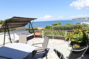 eine Terrasse mit einem Tisch, Stühlen und Meerblick in der Unterkunft Apartment Karmen with sea view in Crveni Vrh