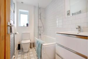 een witte badkamer met een toilet en een wastafel bij Beautifully refurbished cottage in lower Wivenhoe. in Wivenhoe