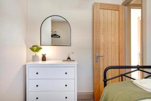 een slaapkamer met een witte dressoir en een spiegel bij Beautifully refurbished cottage in lower Wivenhoe. in Wivenhoe