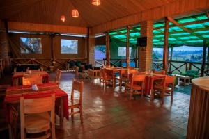 a restaurant with wooden tables and chairs and windows at Apuuli Safaris and Cottages in Kasusu