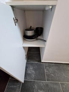 ein Schrank mit zwei Töpfen und Pfannen auf einem Regal in der Unterkunft my TinyPlace in Târgu Mureș