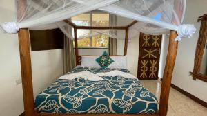 a bedroom with a bed with a blue and white comforter at Aquarium Beach House in Nungwi