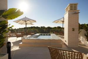 un patio con piscina, sedie e ombrelloni di Belle Marivent Mediterranean Petit Hotel a Palma de Mallorca