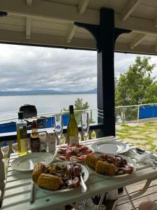 einen Tisch mit Teller mit Lebensmitteln und Flaschen Wein in der Unterkunft Exclusive panorama view of the Oslofjord 