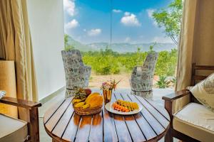 a wooden table with a bowl of fruit on it at Guldaar - A Luxury Forest Retreat in Tehla