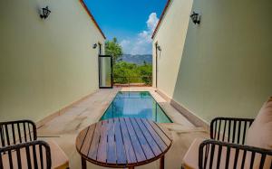 a swimming pool with a table and two chairs at Guldaar - A Luxury Forest Retreat in Tehla
