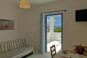 a living room with a couch and a sliding glass door at Spanos Apartments in Agios Petros