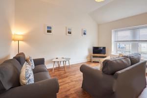 sala de estar con sofá y TV en Host & Stay - Main Street Apartments en Seahouses
