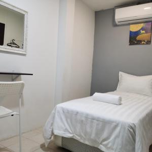 Dormitorio blanco con cama blanca y ventana en Hotel Seroja, en Labuan
