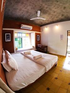 a bedroom with a large white bed with a window at Wow Farm House in Auroville
