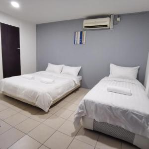 two beds sitting next to each other in a room at Hotel Seroja in Labuan