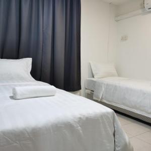 two white beds in a room with blue curtains at Hotel Seroja in Labuan