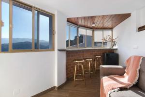 una sala de estar con un bar con taburetes y ventanas en Casa Pepa en Santa Brígida