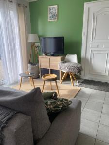 a living room with a couch and a flat screen tv at Petite maison au bord de la forêt 