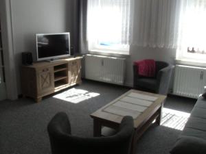 een woonkamer met een tv en stoelen en een tafel bij Monika in Luckenwalde
