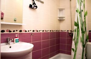 ein Badezimmer mit lila Fliesen, einem Waschbecken und einer Badewanne in der Unterkunft Бодрум in Petropawlowsk
