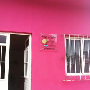 un edificio rosa con una señal rosa en él en Flat e Suítes Praia de São Bento, en Maragogi
