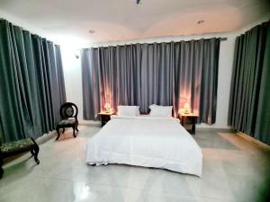 um quarto com uma grande cama branca e 2 cadeiras em A Gorgeous Condo with a kingsize bed em Dar es Salaam