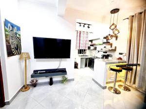 uma sala de estar com uma televisão de ecrã plano na parede em A Gorgeous Condo with a kingsize bed em Dar es Salaam