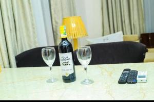 uma garrafa de vinho e dois copos de vinho numa mesa em A Gorgeous Condo with a kingsize bed em Dar es Salaam