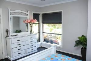 a white bedroom with a dresser and a window at Wetland Gem in Wonthaggi