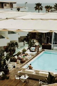 a swimming pool with couches and people sitting around it at Apartamentos Bora Bora - Adults Only in Playa d'en Bossa