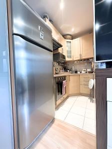 a stainless steel refrigerator in a kitchen with wooden cabinets at Blue apartment in City Center, Best location in Bratislava